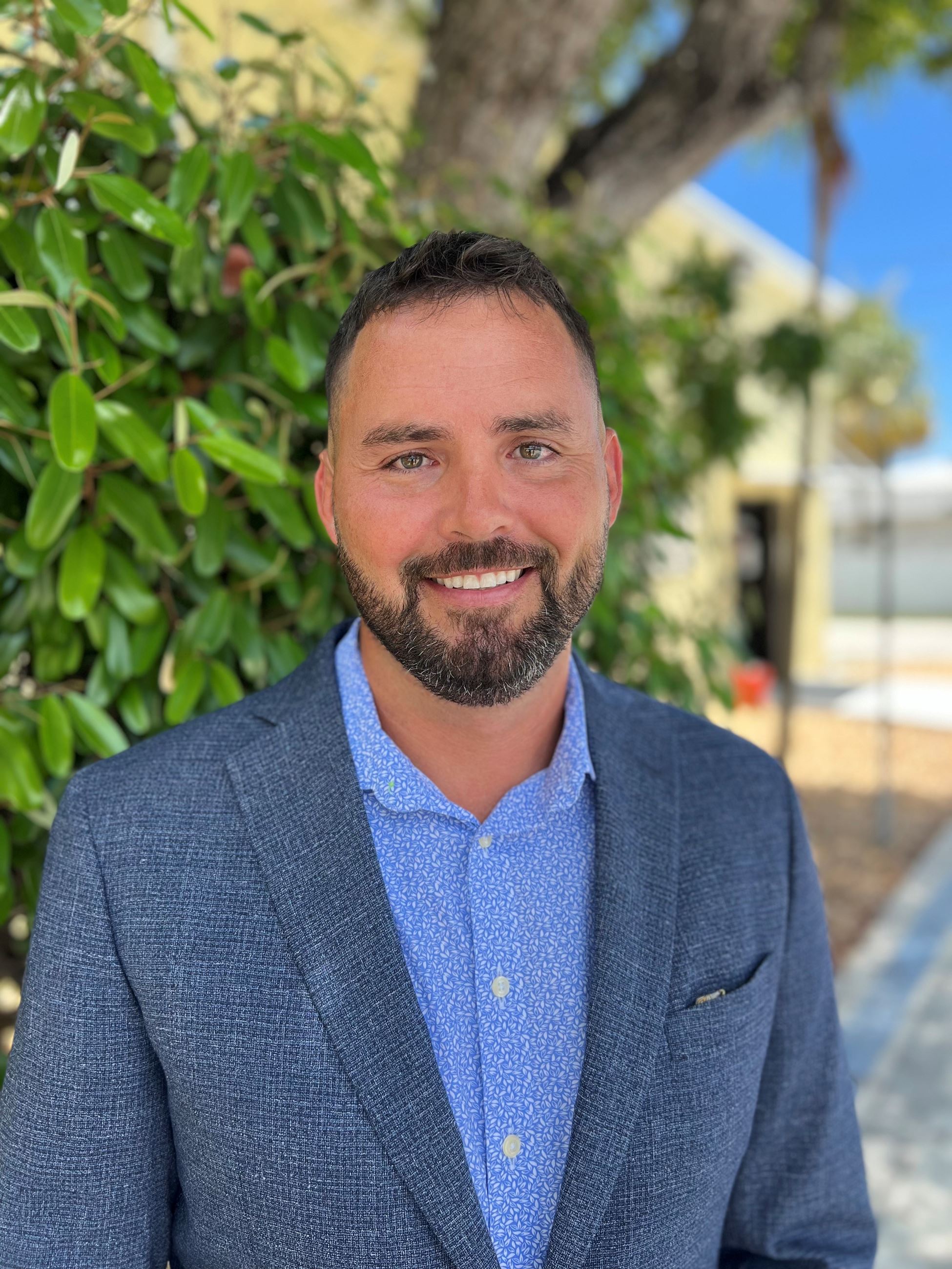 Cory Schwisow headshot outside with greenery behind him